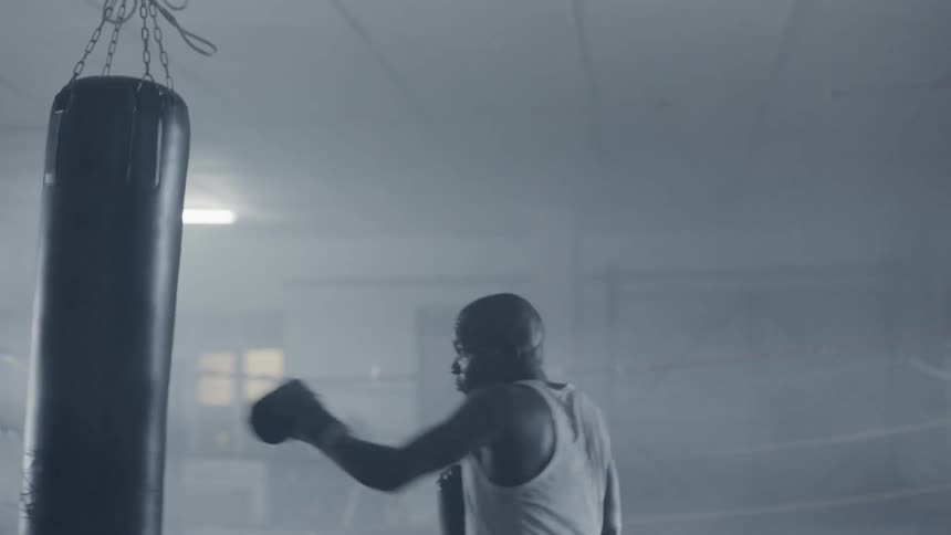 Man wearing boxing gloves punches a punching bag