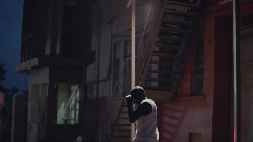 Man is practicing boxing outside city building at night