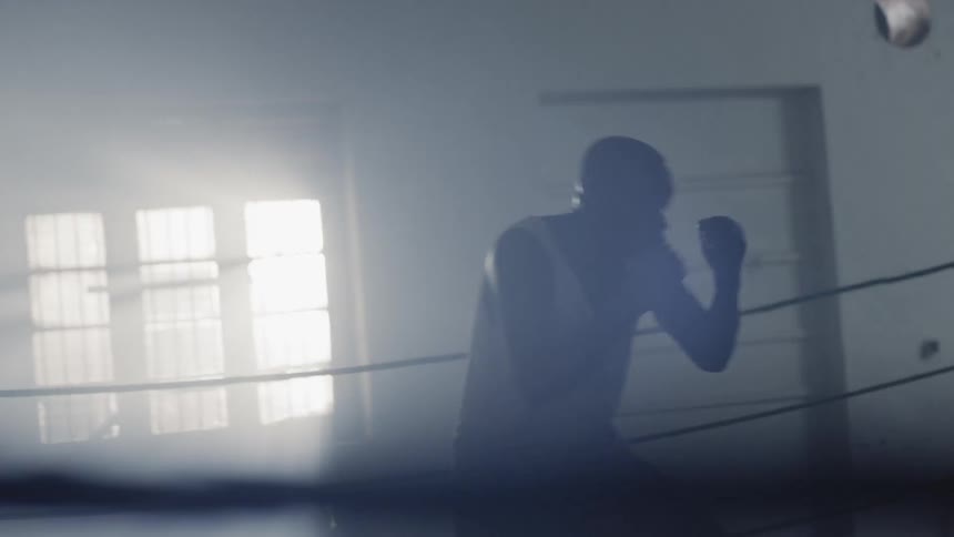 Man is practicing boxing in boxing ring