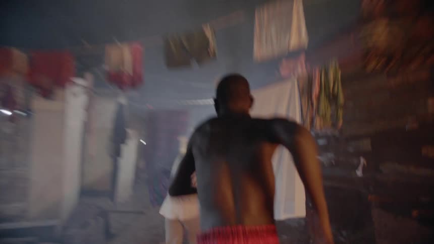 Boy chasing another boy through narrow night street