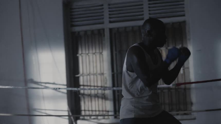 A fighter is shadow-boxing inside a ring