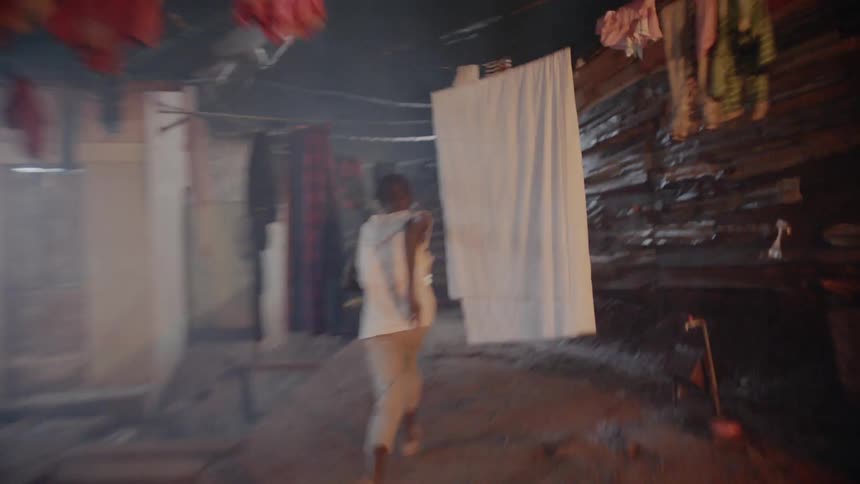 Child runs through a village past hanging clothes at night
