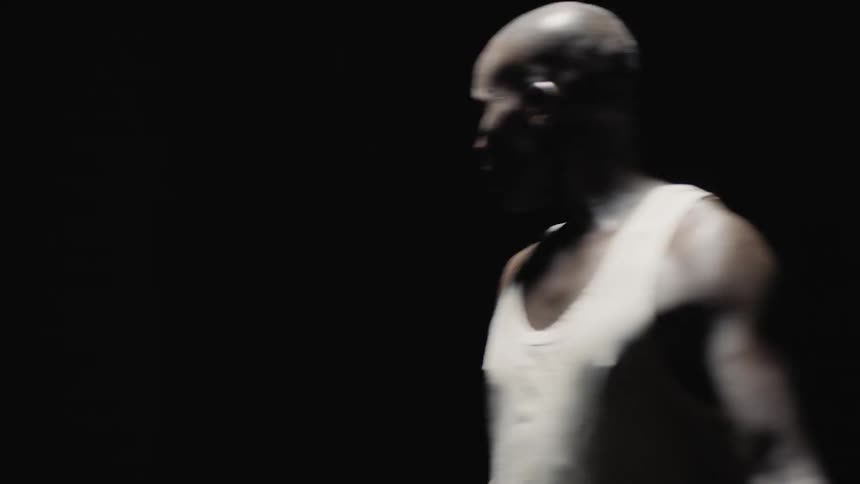 Man in tank top rotates in darkness