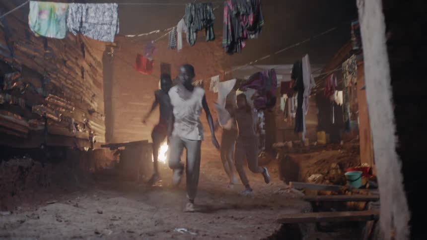 Men push clothes out of the way as they run near the buildings