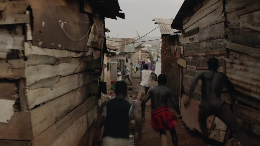 A boy is chased through a village by three larger boys