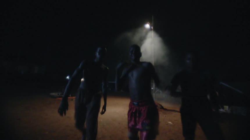 Children run down the field at night attacking someone