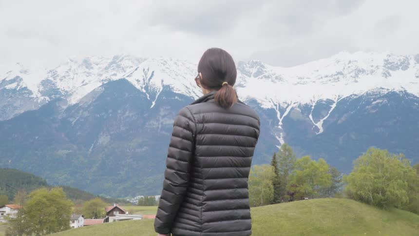 Woman is observing the snowy mountain scenery in the country