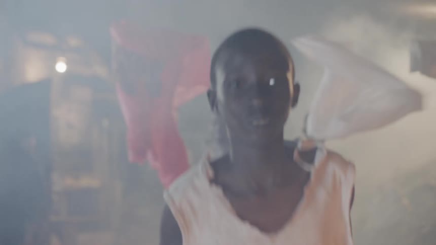 A boy pushes laundry on the line aside as he runs away from others