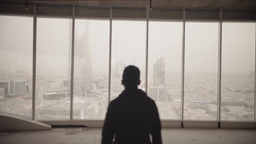 Man walks towards windows in empty high rise