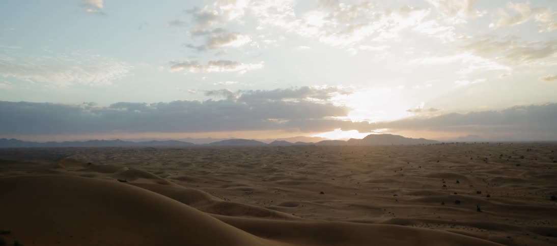 Sun is setting behind vast sand dunes