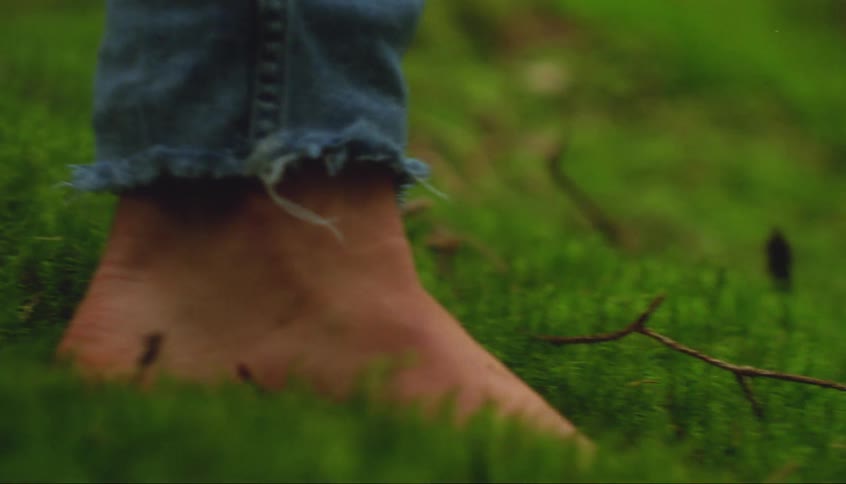 Bare feet walk over the green grass