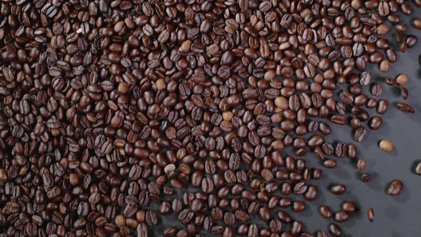 Roasted coffee beans slide over a table