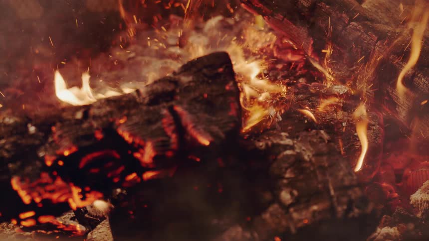 Charred wood falls onto a fire