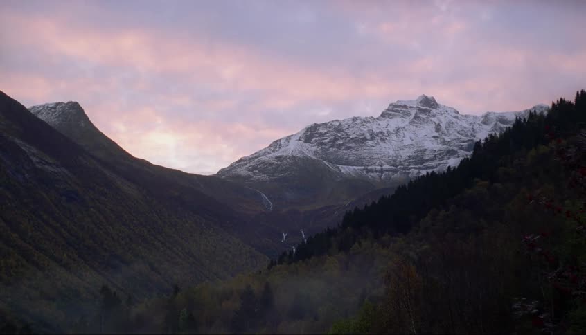 Clouds float above snowy mountains at sunset