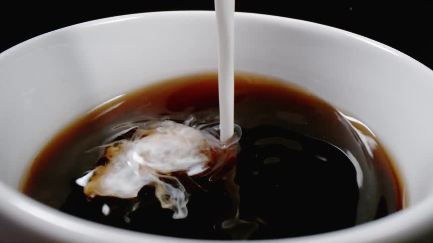 Creamer is pouring into cup of coffee