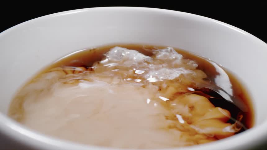Creamer is pouring into cup of coffee