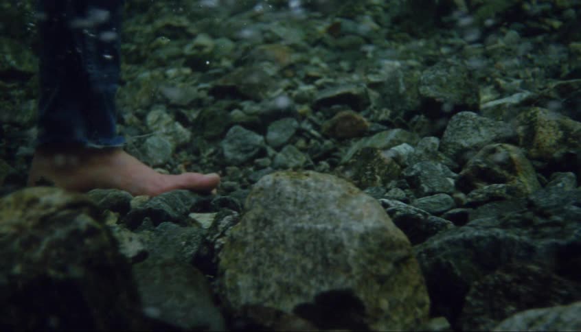 Bare feet walking on underwater stones