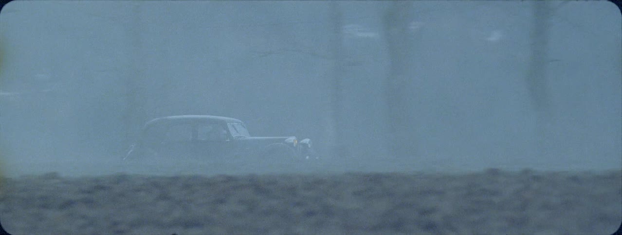 Old car is traveling down country road in the fog