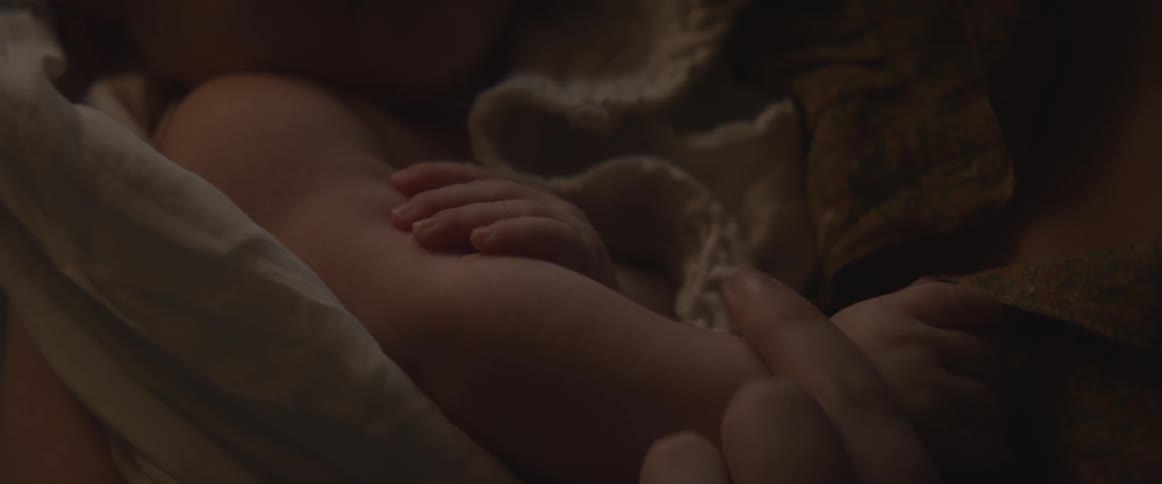 A baby wrapped in a blanket and held by a woman
