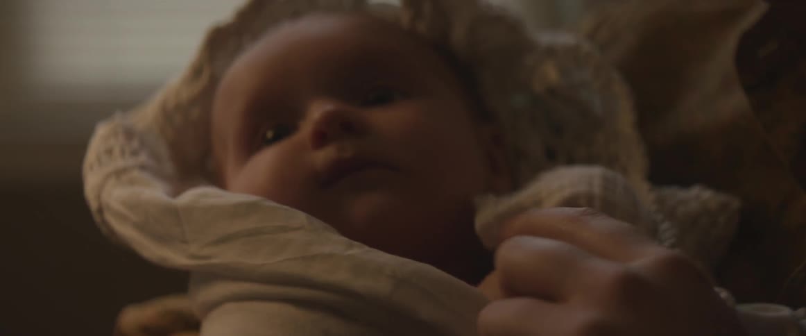 An infant being held and swaddled