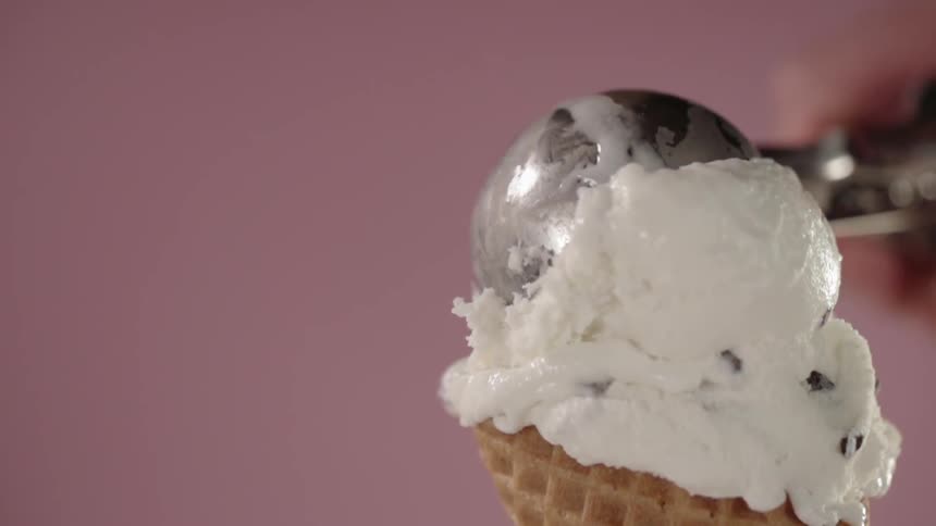 A scoop of ice-cream is being placed into a cone