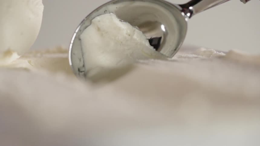 Ice cream scoop scoops a white ball of ice cream