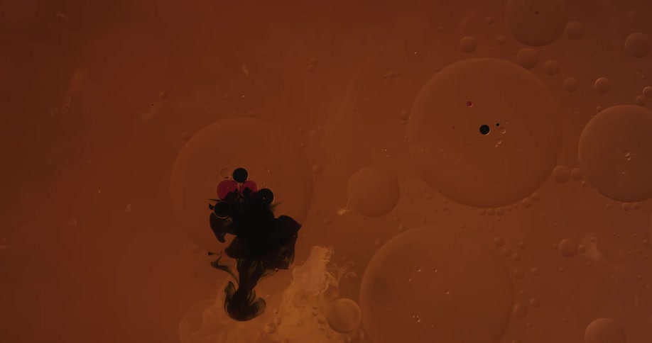 Black liquid flowing in orange liquid
