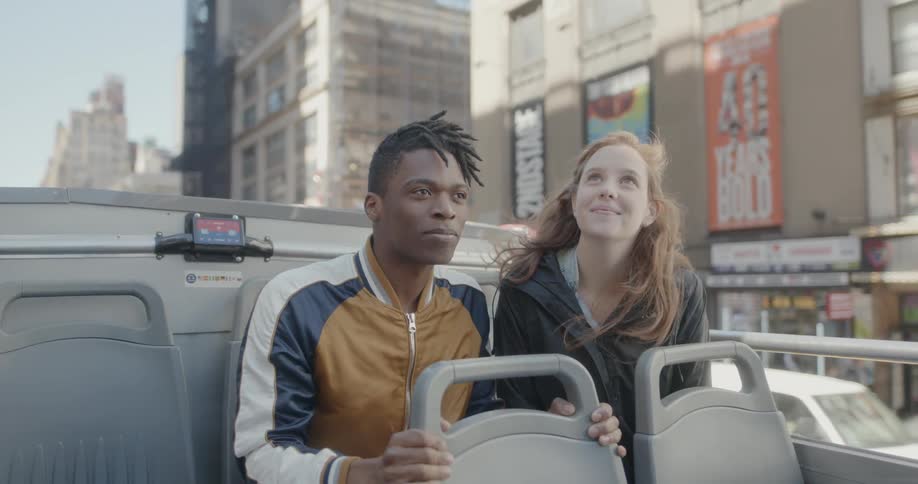 Man and woman sit in a vehicle as it moves down a city street