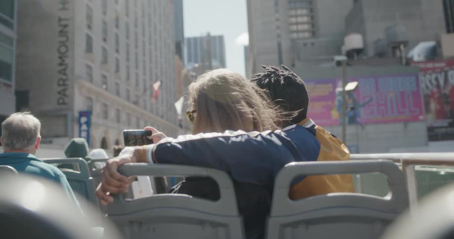 Tourists ride on the roof of a tour bus