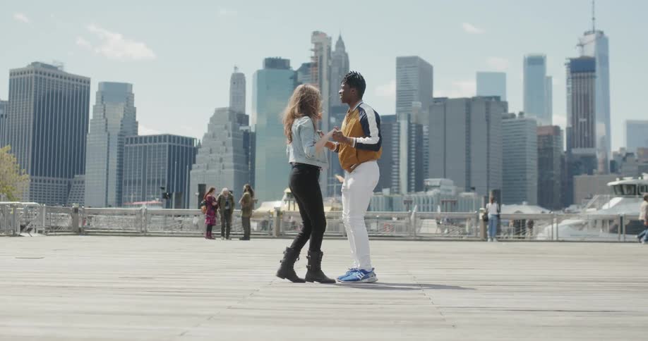 A couple dance in front of the tall buildings