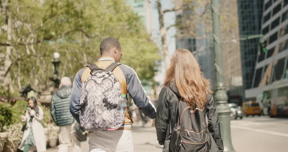 A man and woman hold hands as they walk through the city