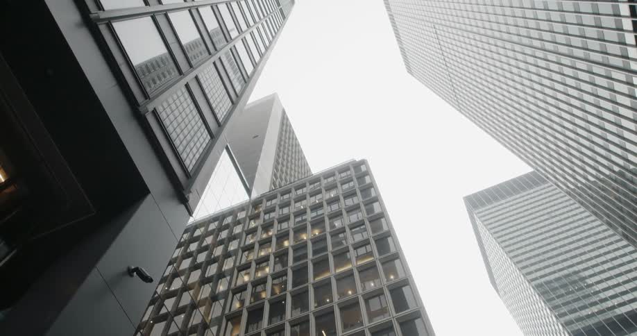 The tall buildings cover the cloudy sky