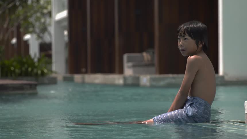 A boy sits in the pool talking