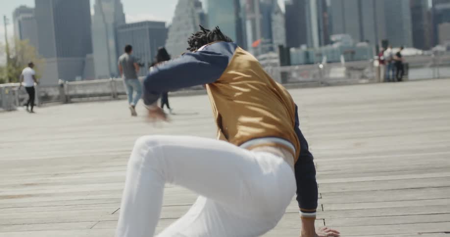 Man dances in a city square on a sunny day