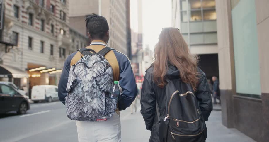 A man and woman walk down the city sidewalk