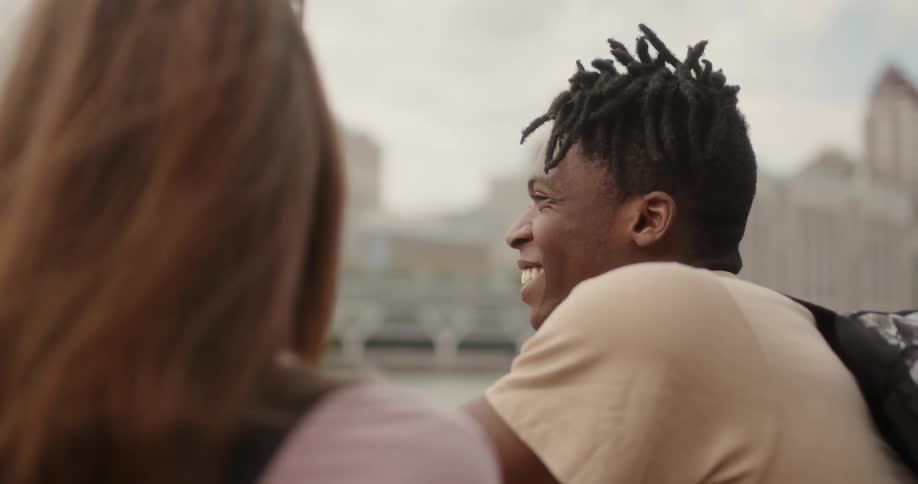 Man smiles looking out across a river at a city
