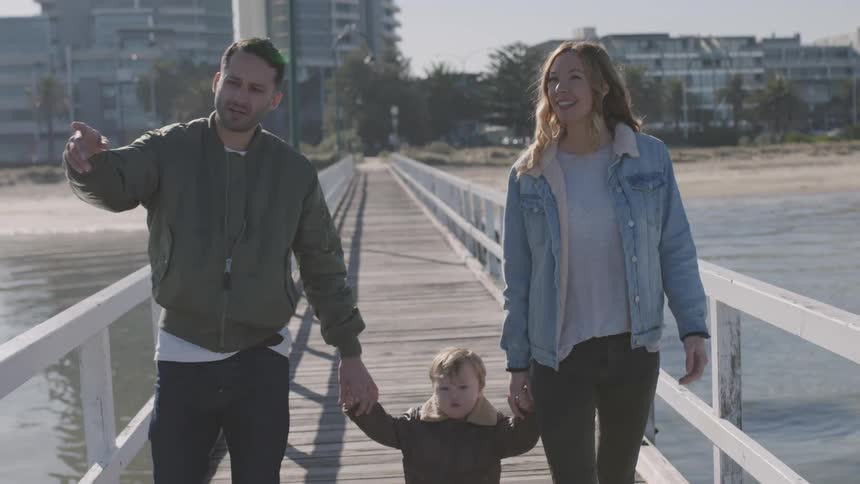 A couple walking on a pier with their young child