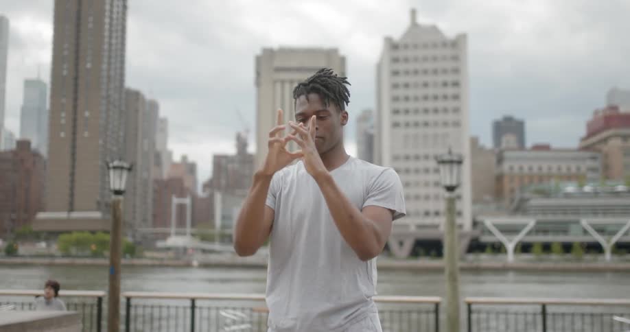 Man break dances beside urban river