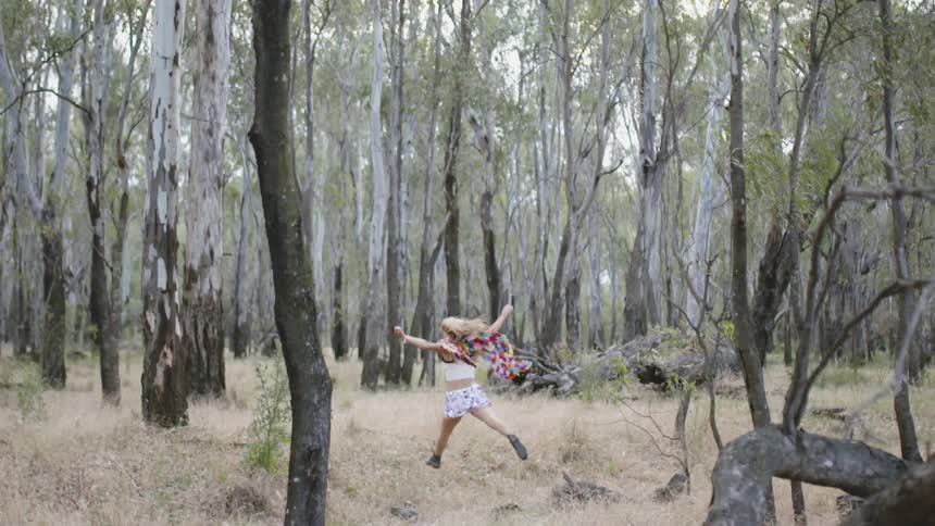 A woman is jumping through the forest