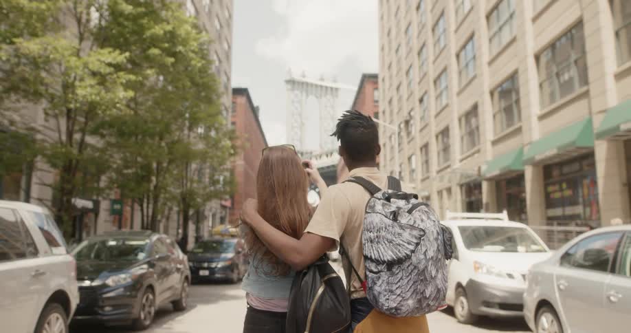 A man and woman take photos with a phone of the tall buildings
