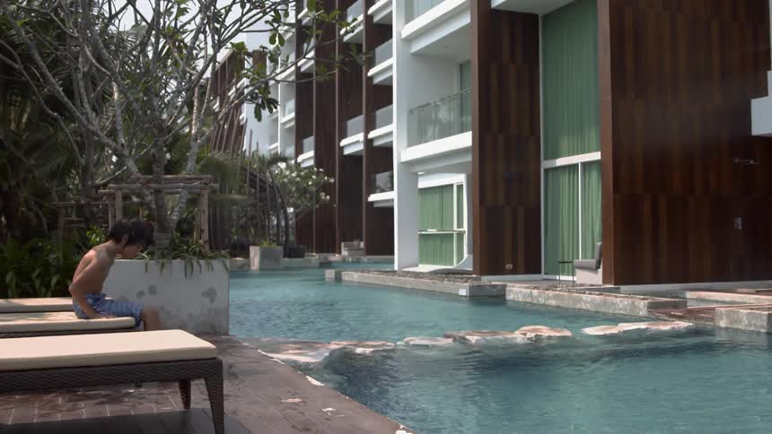 Child sits on a chair looking into a flowing pool