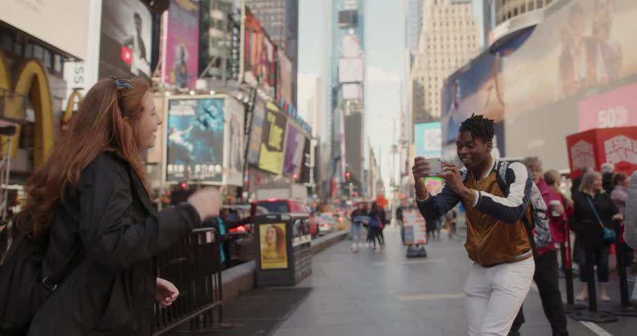 A man takes a picture of a woman in the city