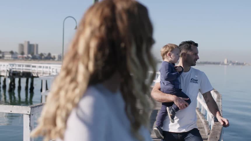 A man holds a young boy on the pier