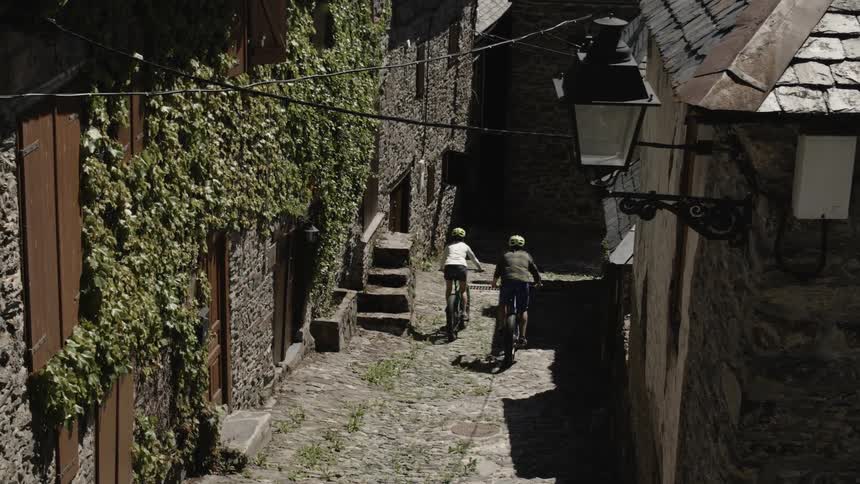 Two cyclists pass through an adorable stone village