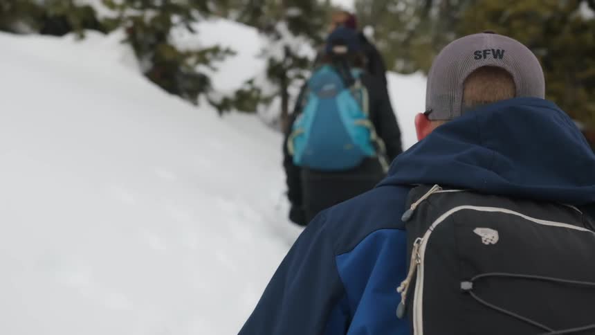 People are hiking through the snow on the hill