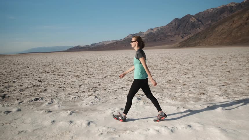 A woman walks on a salt lake bed on a sunny day