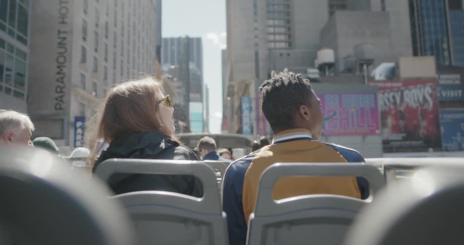 The tour bus has many people sitting at the top