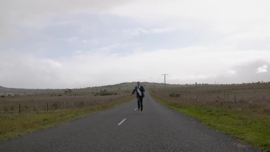 A man in a suit is racing down the road