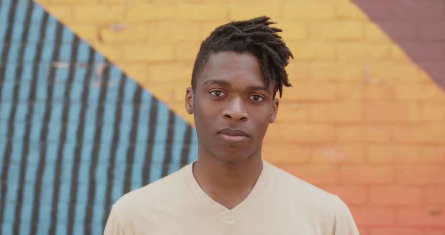 A man is posing for a photo in front of a brick wall