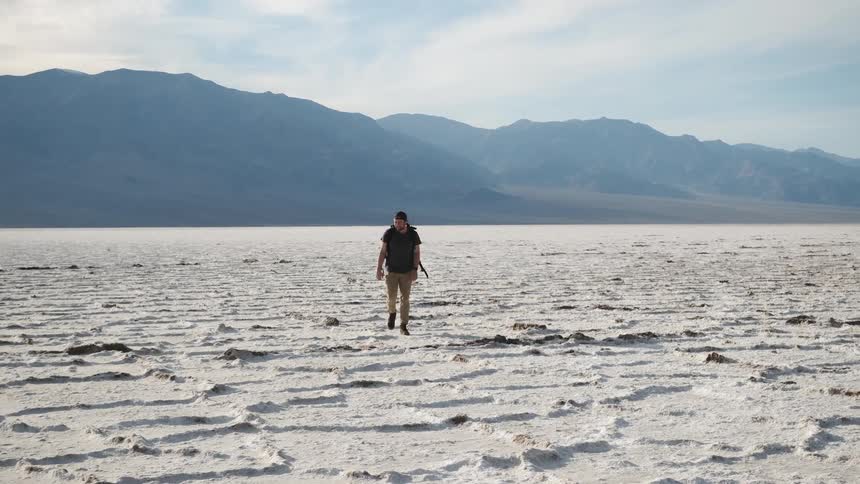 A person hikes in the valley of a salt lake bed